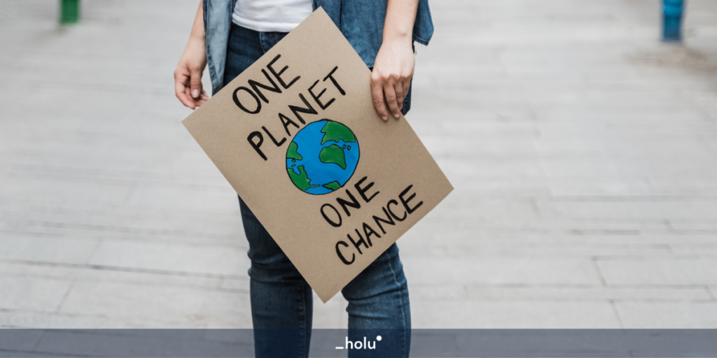 Pessoa com os braços abaixados segurando um cartaz com o desenho do planeta, escrito "one planet, one chance".