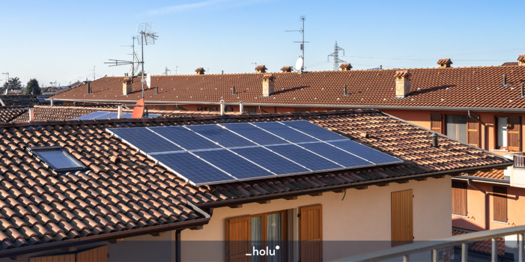 Placas solares instaladas no telhado de uma casa rosa, abaixo de uma janela