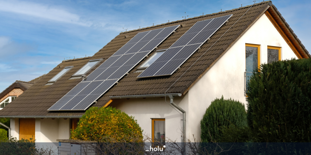 Casa branca com placas de energia solar instaladas no telhado e arvores em volta