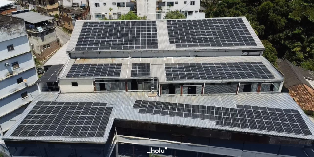 Foto de cima de um edifício comercial, com diversas placas solares cobrindo todo o telhado. Foto real do projeto B2B em energia solar.